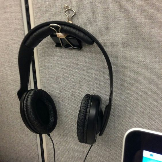 Make a headphone holder by twisting a rubber band around the two metal clasps and pinning the binder clip on the wall